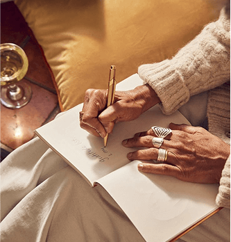 Mid-age woman sitting on a couch, taking notes on her notebook