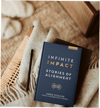 Book cover of the Infinite Impact book written by Amber Vilhauer on top of a wooden chair with a pen next to it
